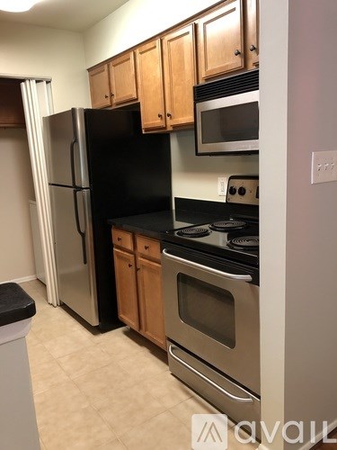 A kitchen with a black refrigerator and stove top oven.