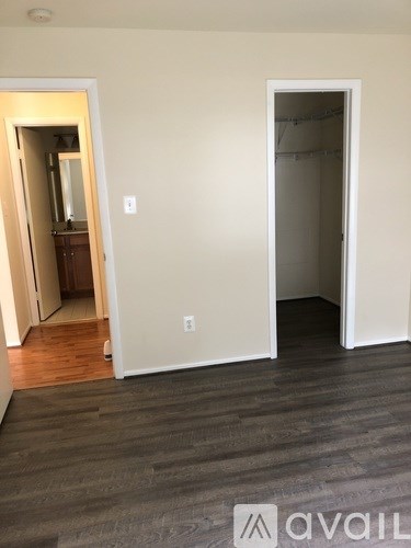 A room with a doorway leading to another room and a wooden floor.