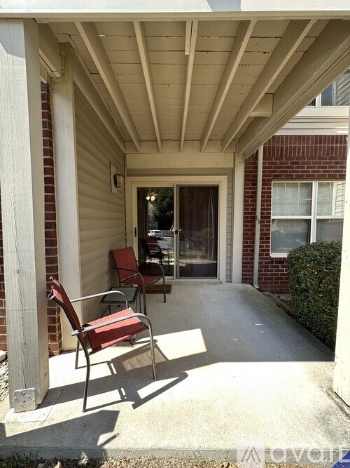 A red chair is on a porch with a white ceiling.