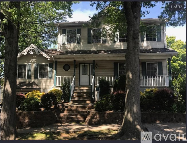 A two-story house with a front porch and a tree in front.