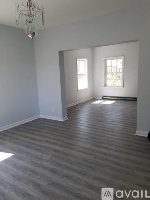 A room with grey flooring and a chandelier.