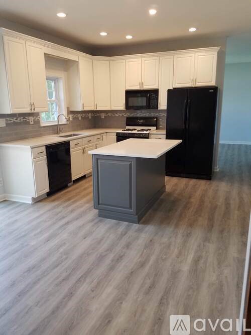 A kitchen with black appliances and white cabinets.