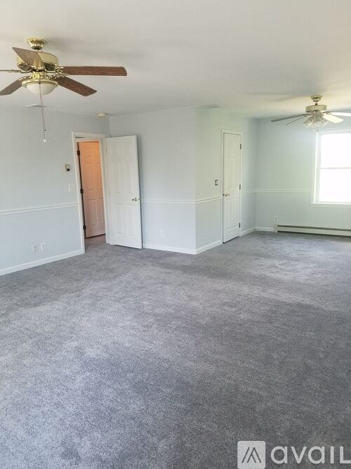 A room with a carpeted floor and two ceiling fans.
