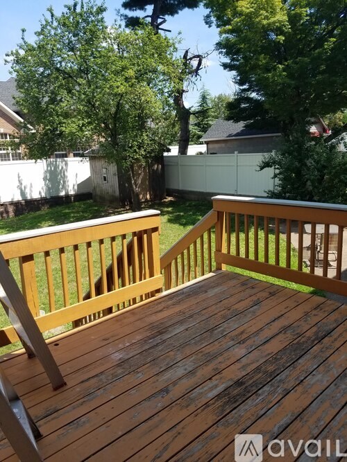 A wooden deck with a railing and steps leading up to a house.