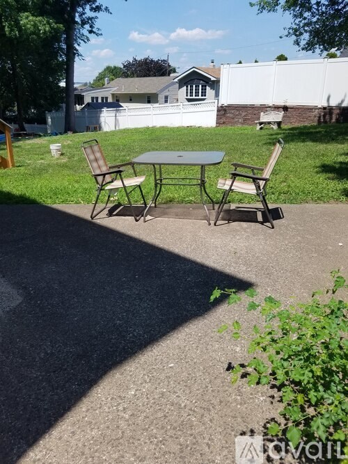 A grey table and two chairs are on a concrete surface.