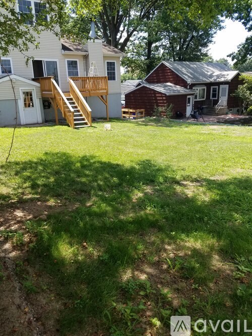 A backyard with a white house and a red barn.