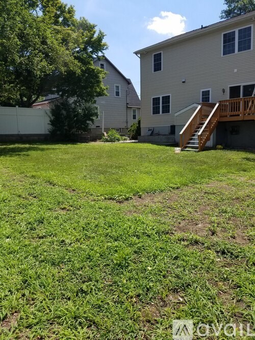 A backyard with a house, a tree, and a wooden deck.