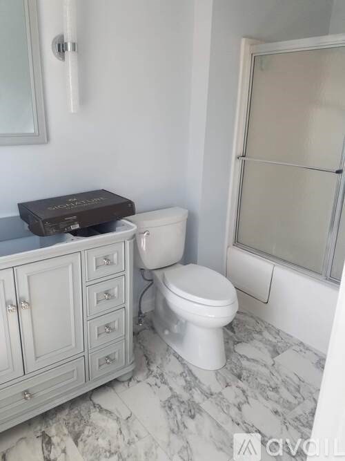 A white toilet sits next to a white cabinet in a bathroom.