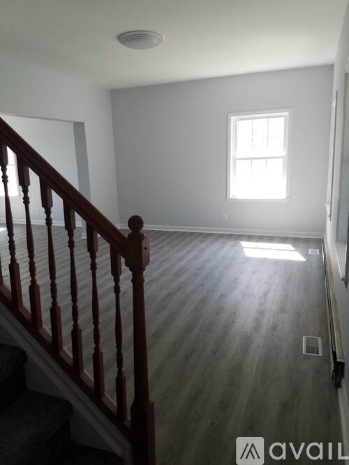 A room with wooden stairs leading to a window.