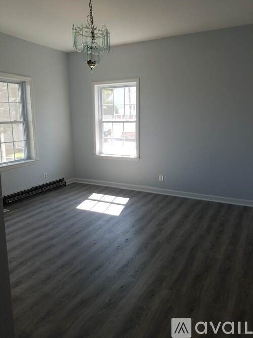 A room with wooden floors and two windows.