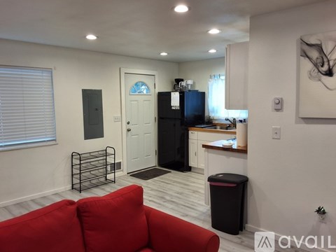 A living room with a red couch and a black fridge.