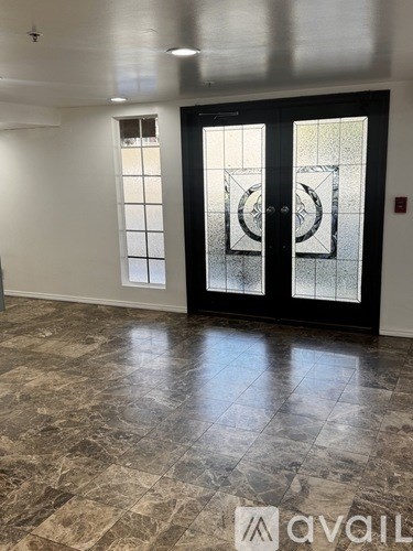 A hallway with marble flooring and a glass door with a circular design.