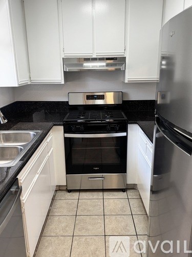A kitchen with a black stove top oven and a stainless steel refrigerator.