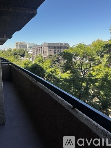 A balcony with a view of a cityscape and trees.