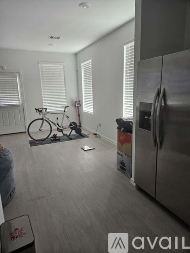 A kitchen with a refrigerator, a bicycle, and a vacuum cleaner.