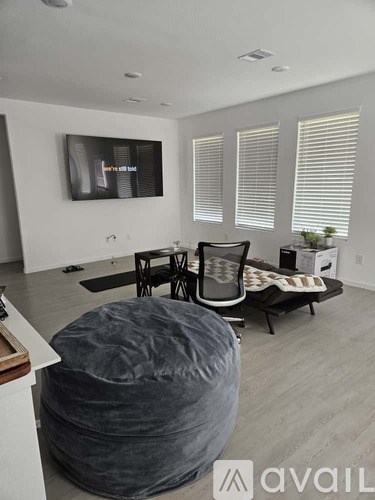 A living room with a grey bean bag chair and a black and white striped couch.