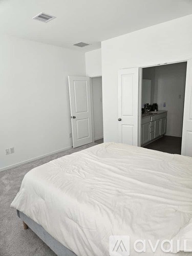 A bedroom with a large bed and a small kitchen area.