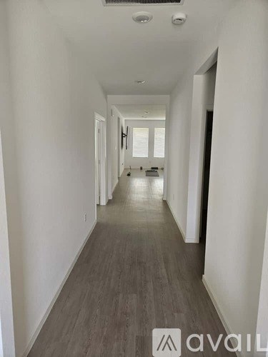A long hallway with wood flooring and white walls.