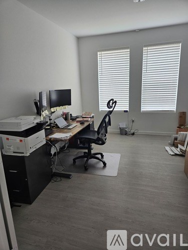 A room with a desk, chairs, and computer monitors.