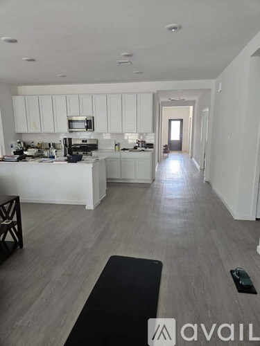 A kitchen with white cabinets and a black mat on the floor.