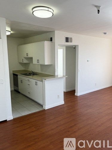 A kitchen with white cabinets and a wooden floor.