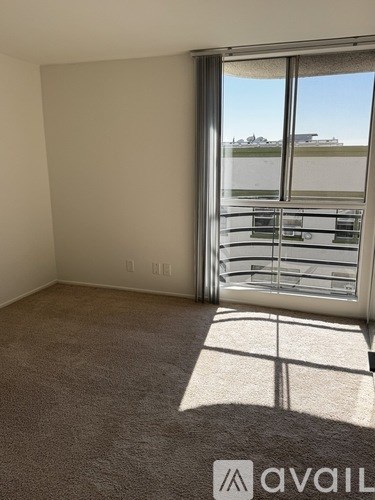 A room with a carpeted floor and a sliding glass door leading to a balcony.
