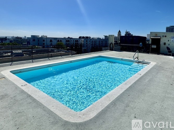 A swimming pool on a rooftop with buildings in the background.