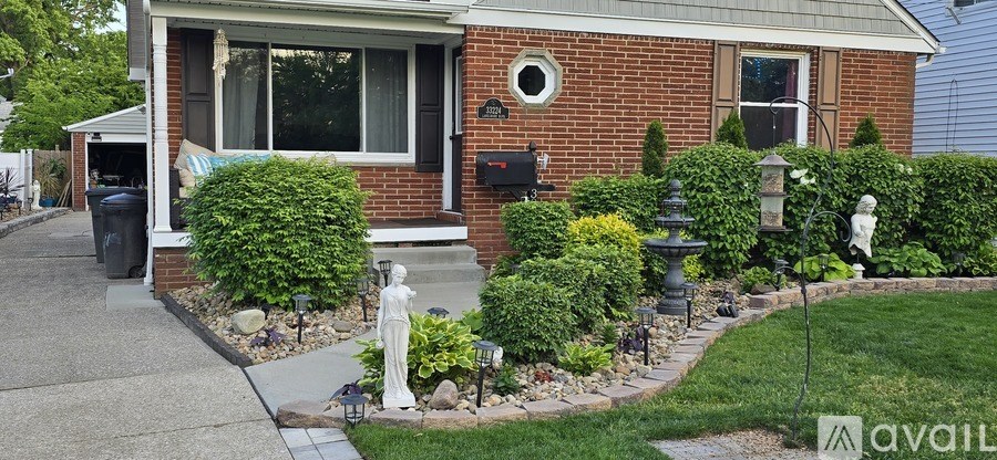 A red brick house with a white statue in front.