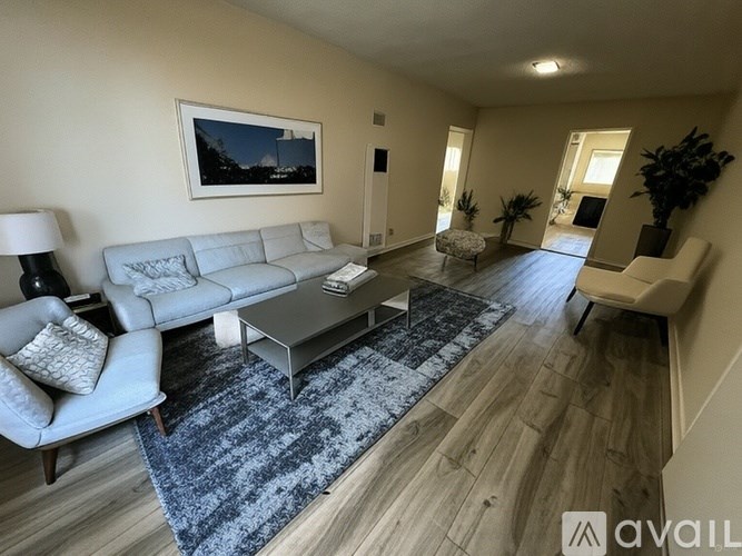 A spacious living room with a grey sofa, a coffee table, and a rug.