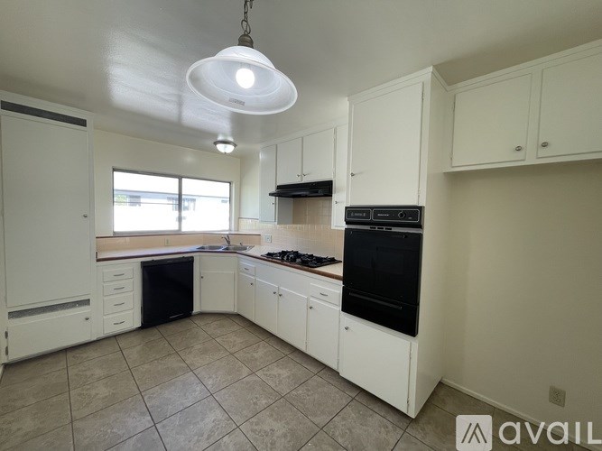 A kitchen with black appliances and white cabinets.