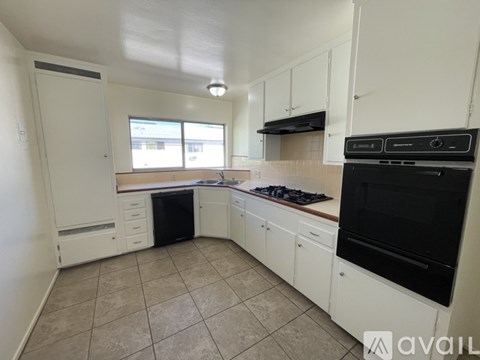 A kitchen with white cabinets and black appliances.