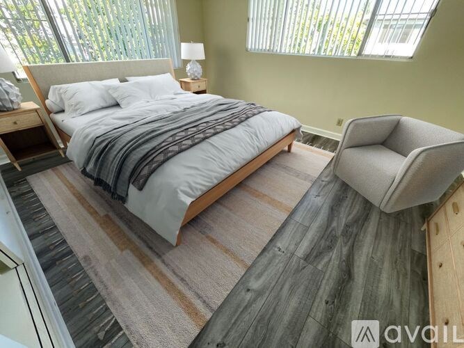 A bedroom with a large bed and a chair.