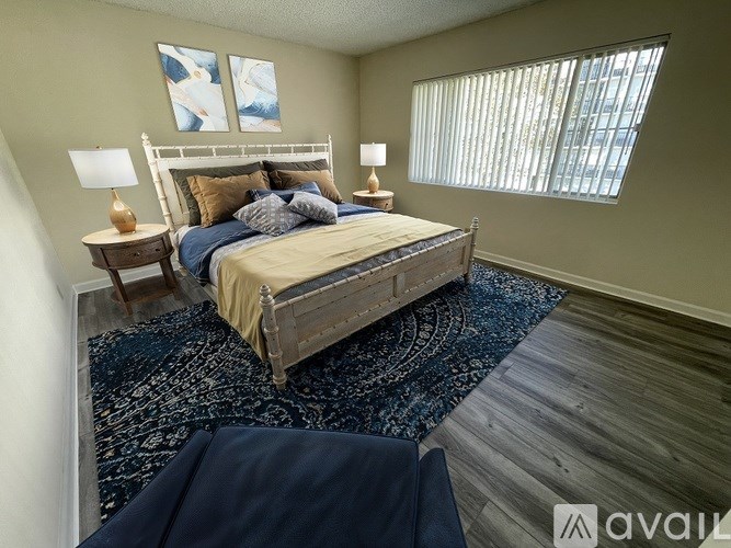 A bedroom with a large bed and two lamps.