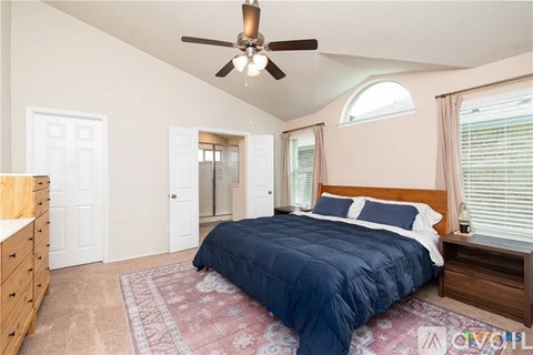 A bedroom with a bed, dresser, and ceiling fan.