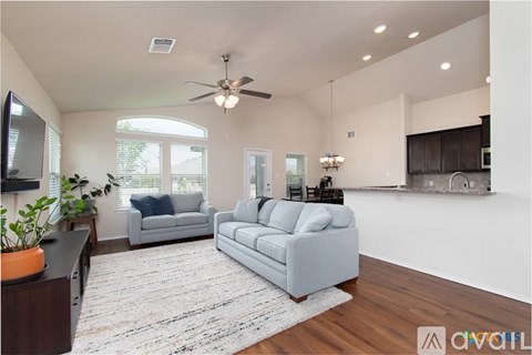 A living room with a grey couch and a ceiling fan.