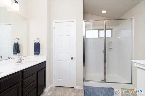 A bathroom with a white door and a glass shower stall.