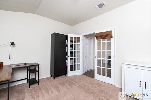 A room with a black cabinet, a desk, and a white door.