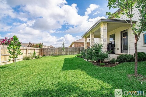 A house with a fence and a tree in the front yard.