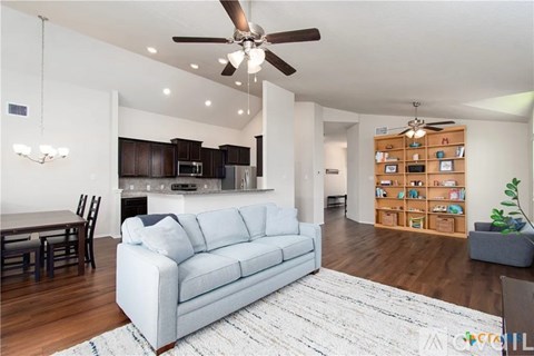 A living room with a grey couch and a ceiling fan.