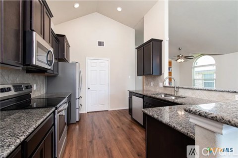 A kitchen with dark brown cabinets and granite countertops.