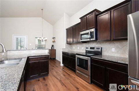 A kitchen with dark wood cabinets and stainless steel appliances.