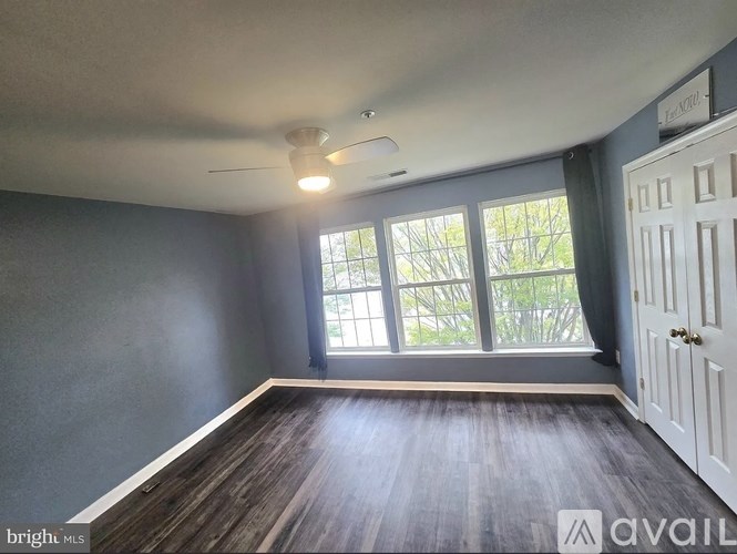 A room with a ceiling fan and a large window.
