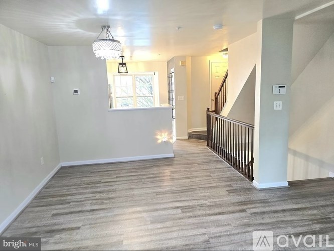 A spacious room with wooden flooring and a staircase on the right side.