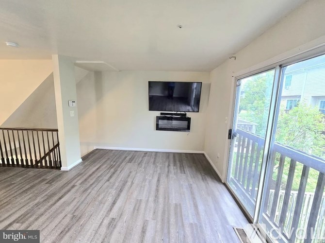 A spacious living room with a television and a staircase.