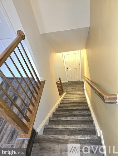 A staircase with a wooden handrail and a carpeted runner.