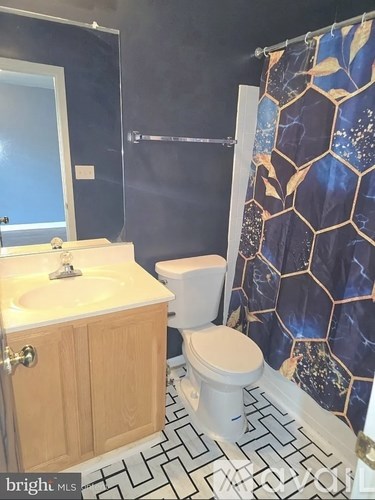 A bathroom with a toilet, sink, and shower curtain.