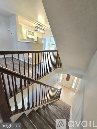 A staircase with a wooden handrail and a carpeted runner leads to a second floor.
