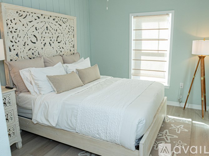 A bed with a white comforter and pillows in a room with a wooden headboard.