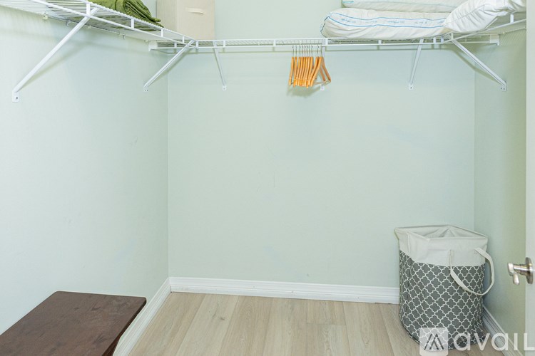 A white closet with a hanging shelf and a bag on the floor.