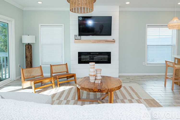 A living room with a fireplace and a television mounted above it.